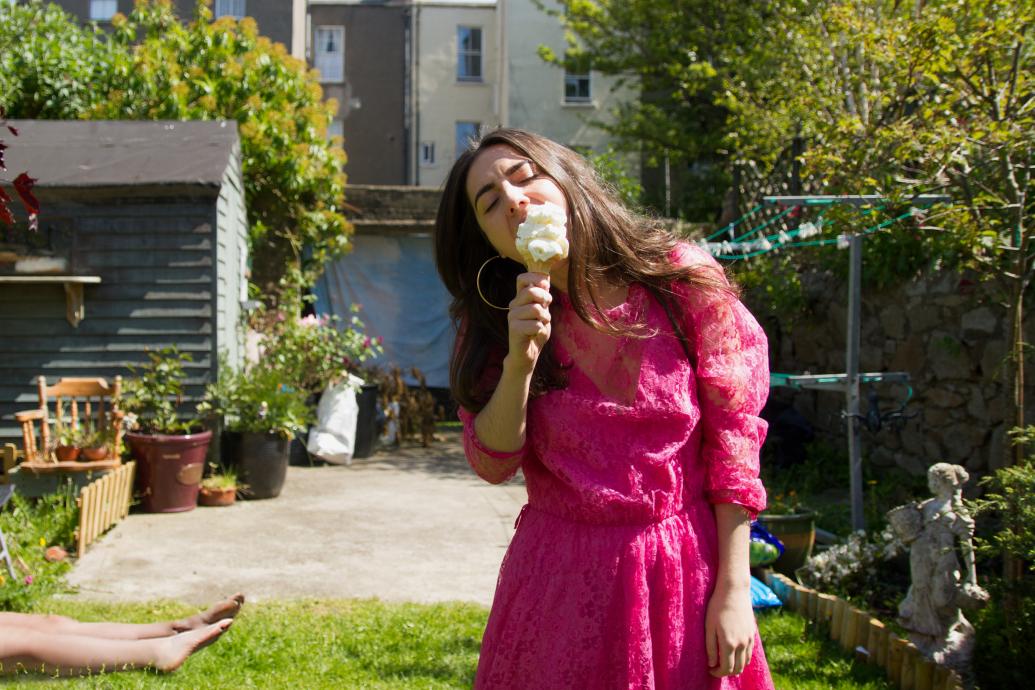 Woman eating an ice-cream, with a body in the background