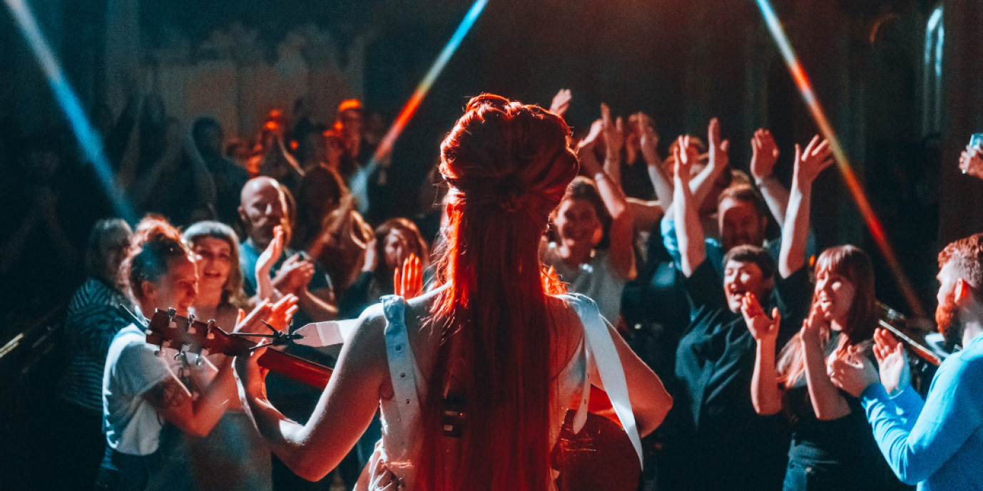 a view from behind the artist performing looking at an incredible audience 