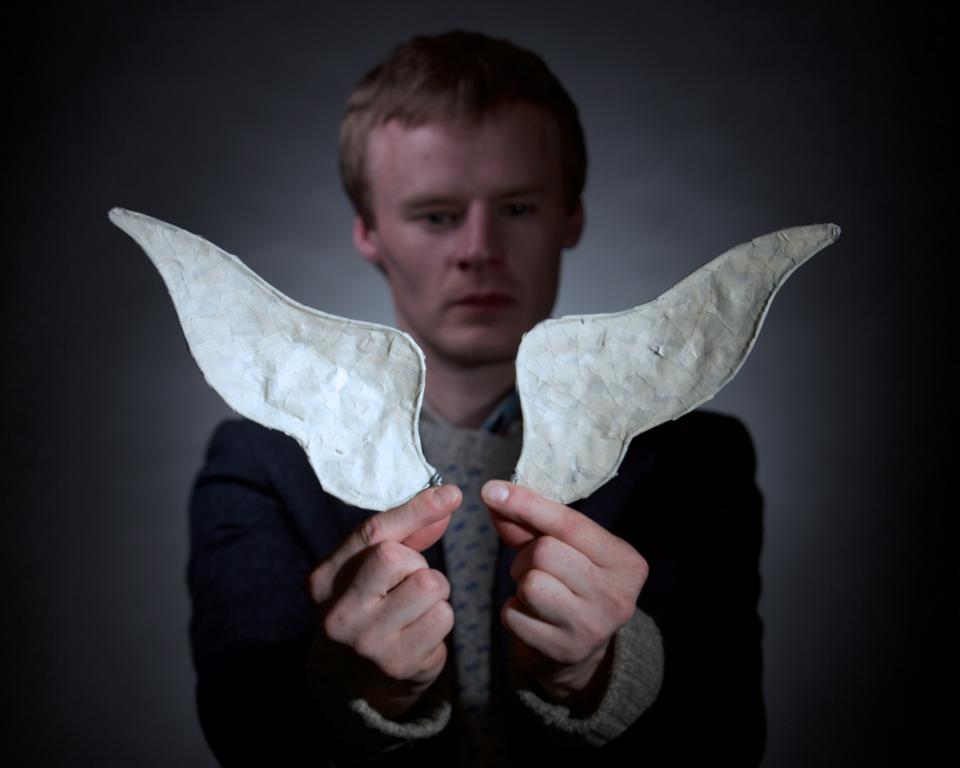 a man holding a small pair of wings in front of him