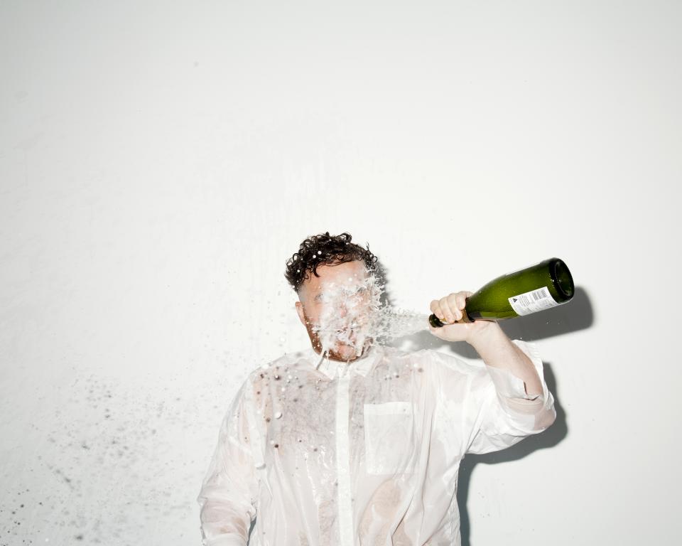 Man throwing prosecco into his face