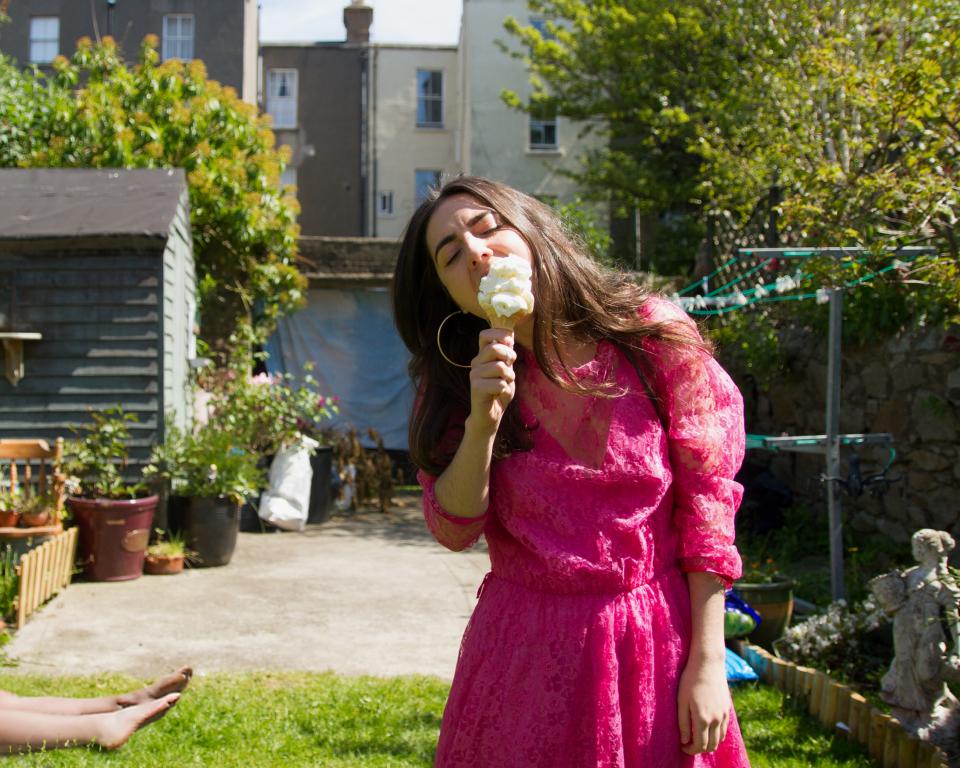 Woman eating an ice-cream, with a body in the background