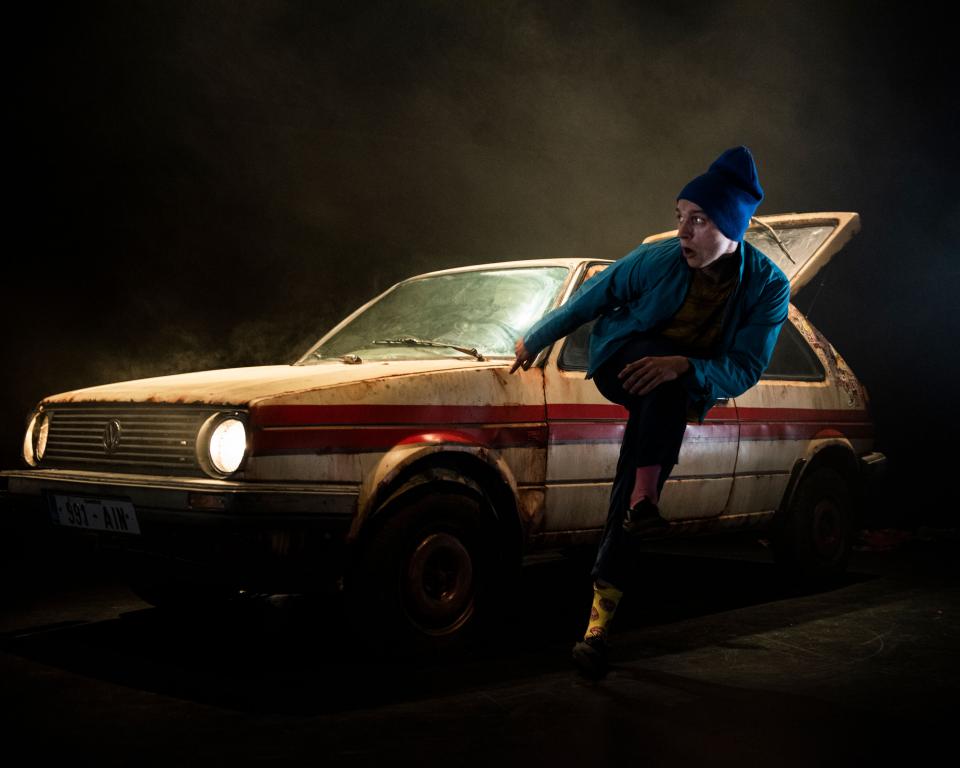 Young man dancing in front of a car with a dark background