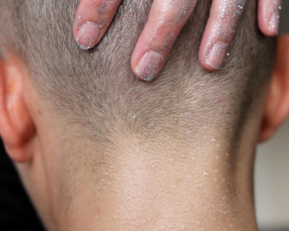 A hand with glitter holding the back of a head