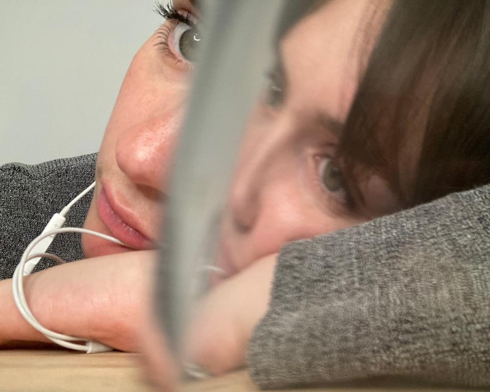 A woman listening to headphones obscured by a glass