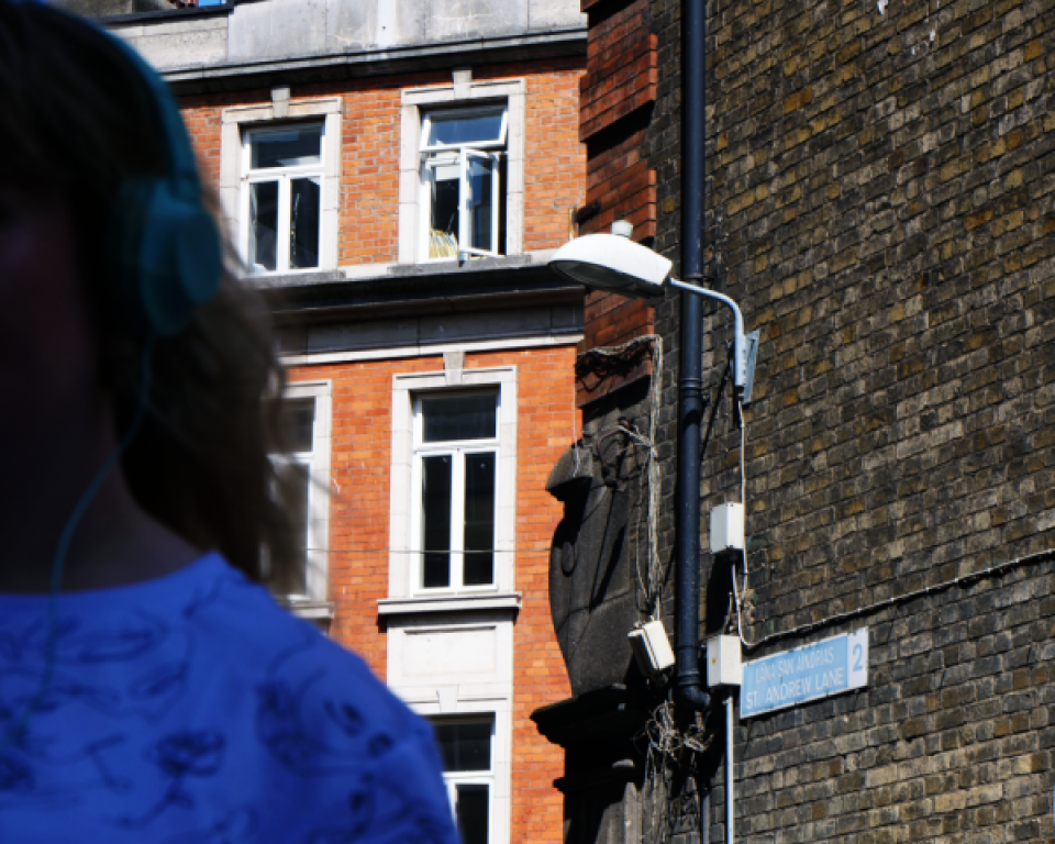 Woman standing in a Dublin lane listening to headphones