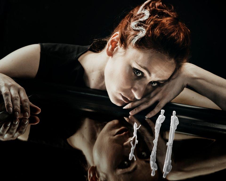 A woman leaning on a reflective table indoors, with three ghostly miniature figures standing on the table