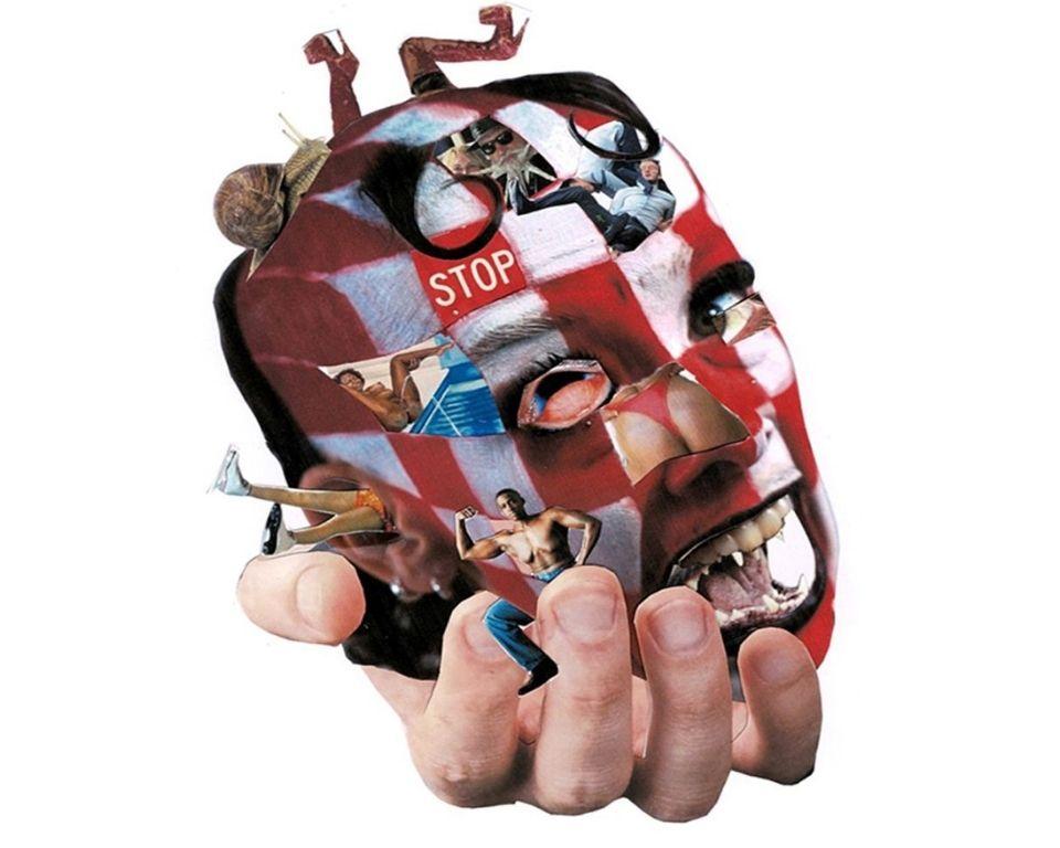 A hand holding a face. There are various characters and designs present on the head.