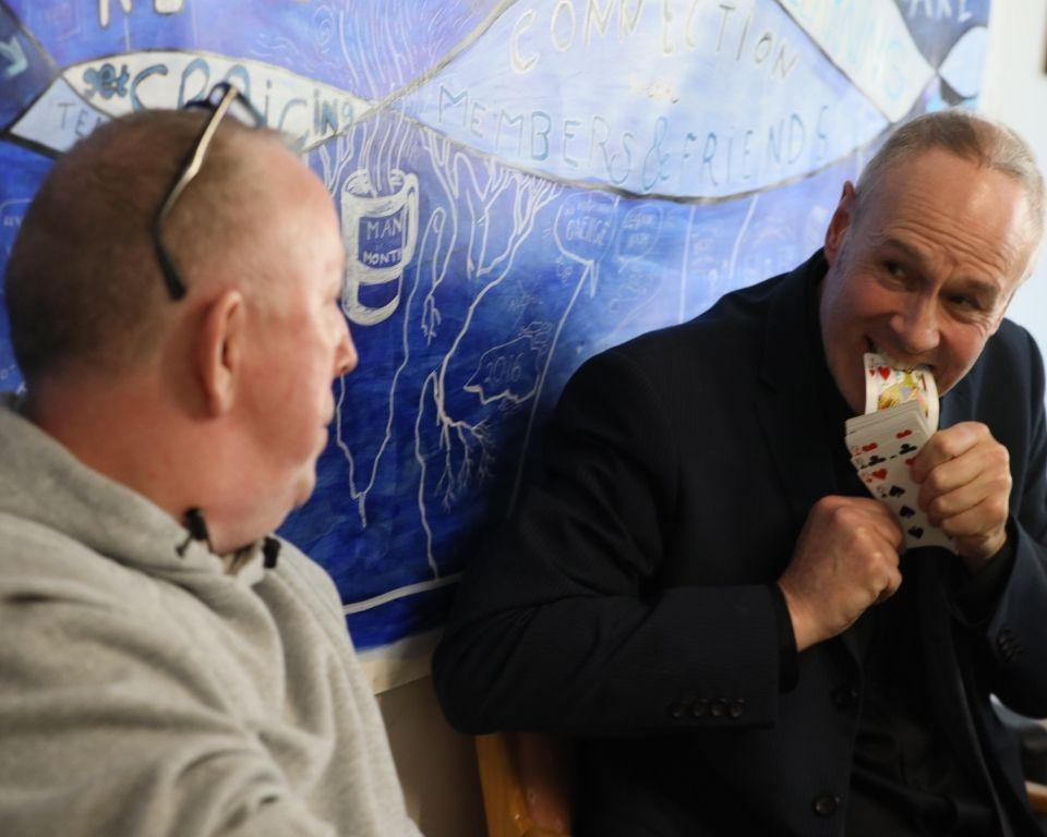 Two Men talk to each other in front of a blue wall