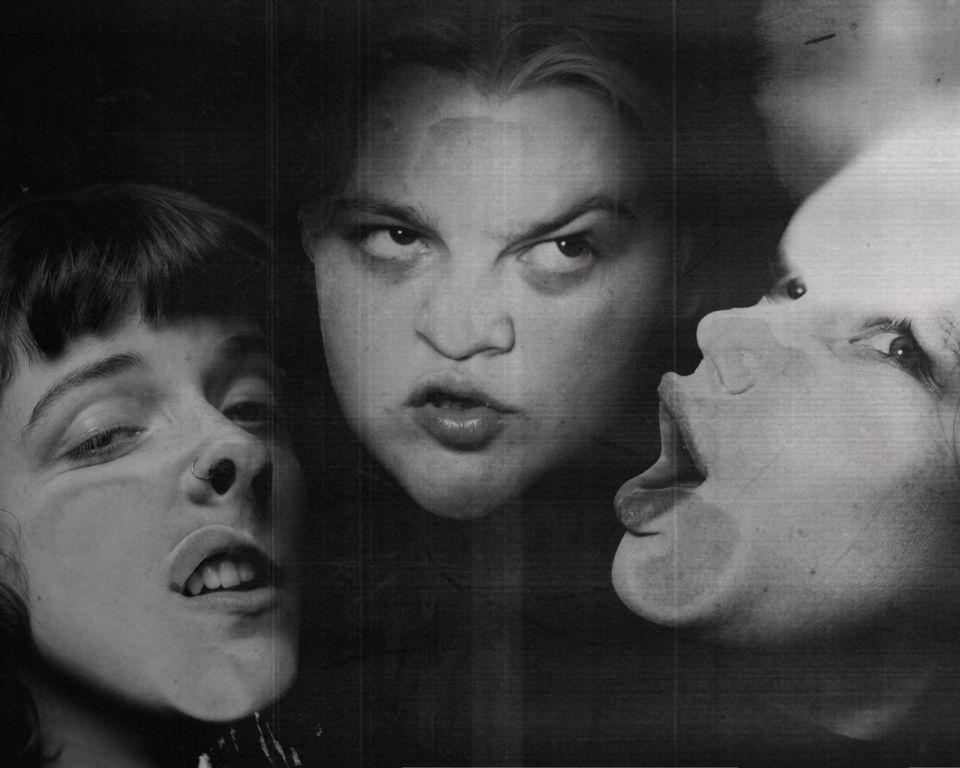 Three women with open mouths, one making a funny face, expressing surprise or excitement in a lively setting.