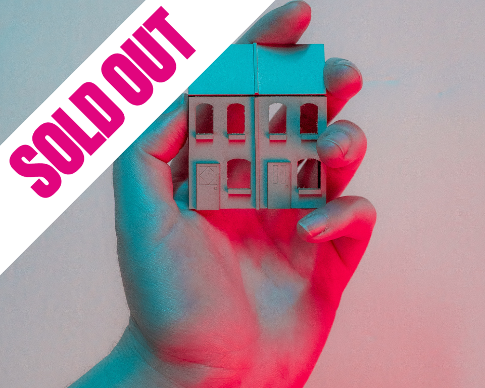 A person gently holds a small house in their hand, symbolizing care and ownership.