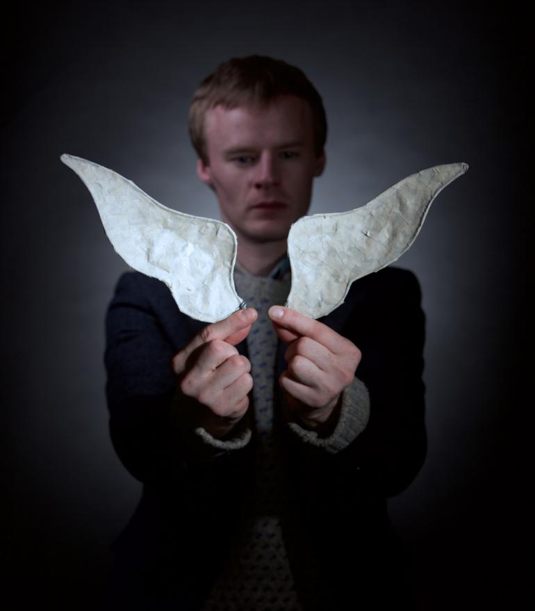 a man holding a small pair of wings in front of him