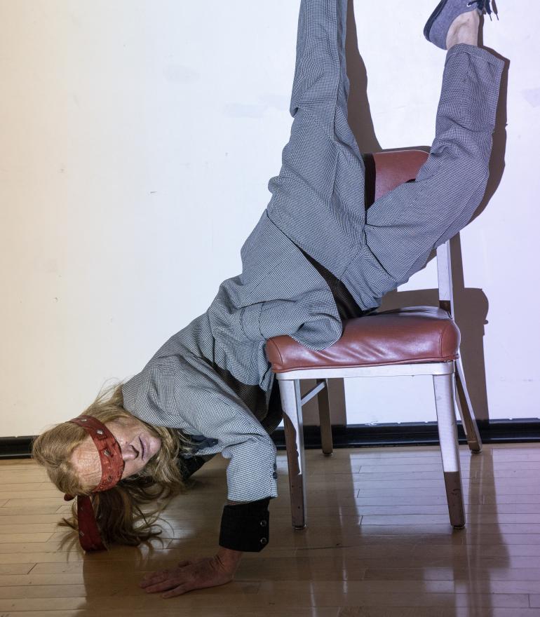 Circus, woman with hands on floor upsidedown on chair