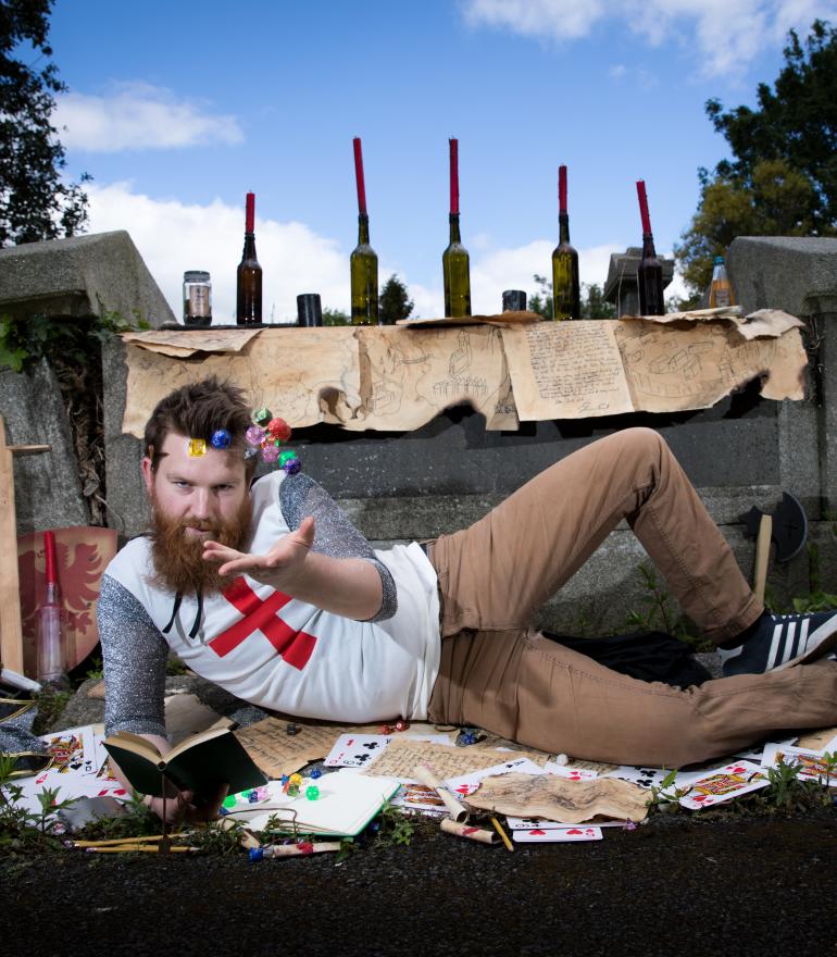 man surrounded by dungeons & dragons items throwing dice in the air