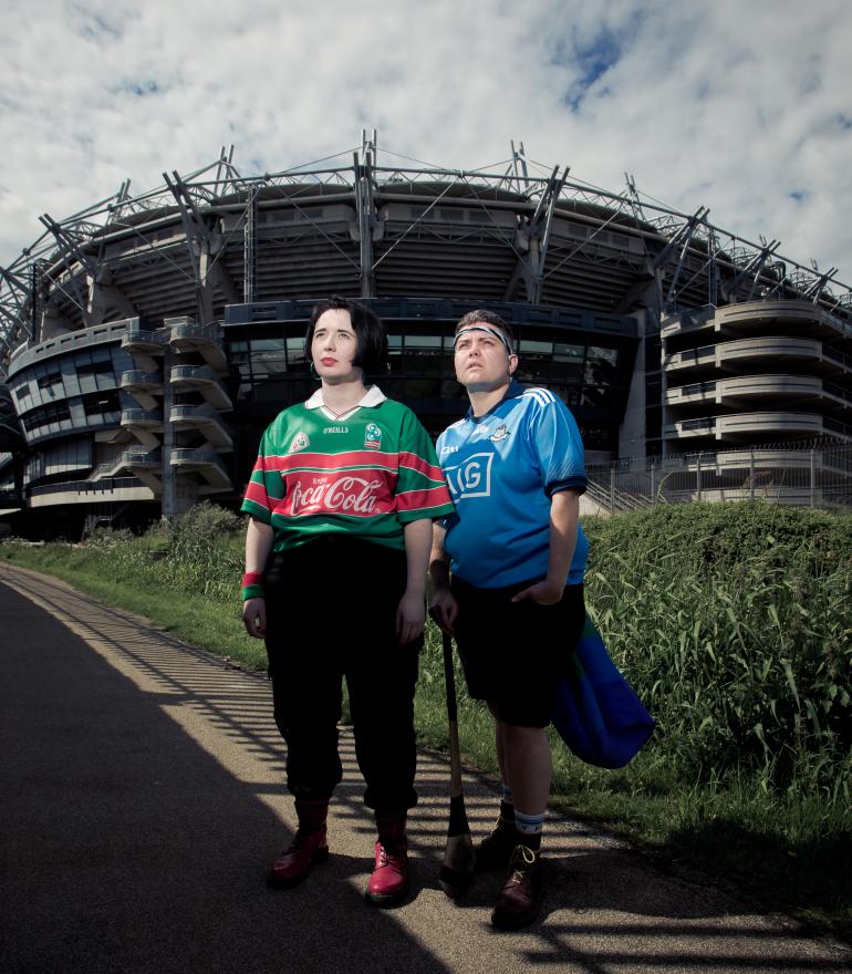 Two people stand in GAA jerseys outside of Croke Park