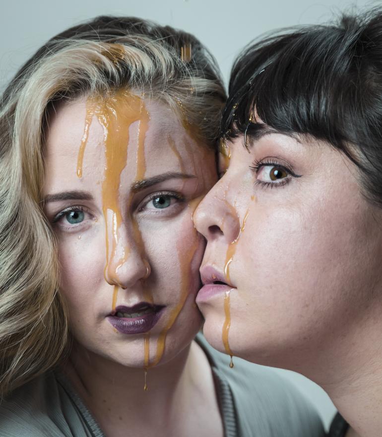 two women face to face with sauce on them