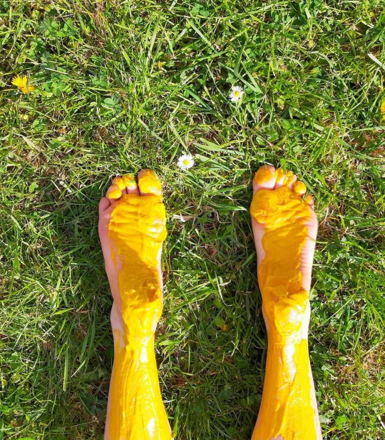 Woman spreading mustard on herself in a fiel