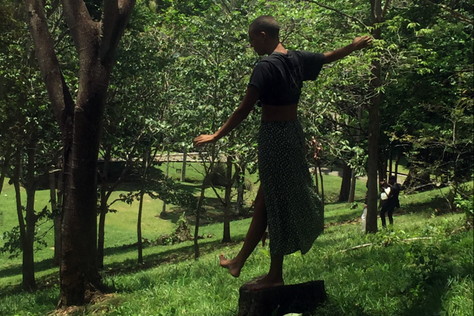 Woman balancing on tree trunk in wooded area