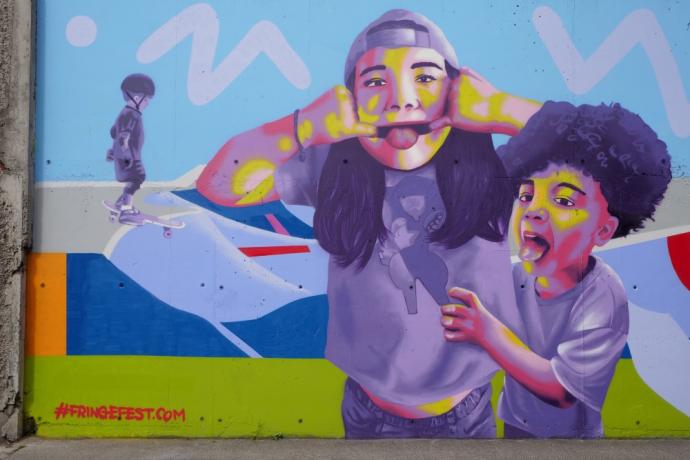 Wall mural of children sticking their tongues out by artist Emmalene Blake