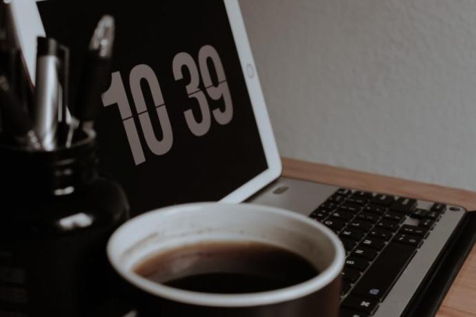 Coffee cup and laptop displaying the time of 10.39