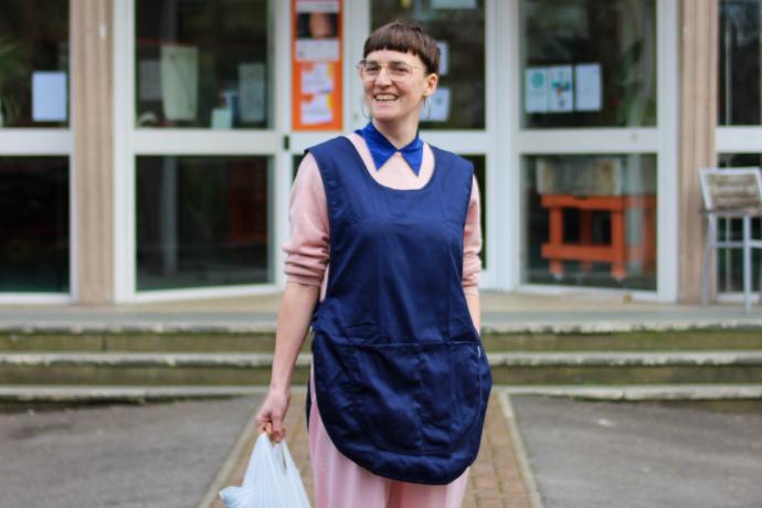 Portrait of artist Rachel Clerke holding shopping bag wearing a cashiers smock