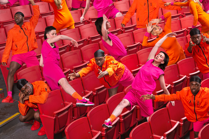 Multiples of bodies in pink red and orange costume in various poses of relection