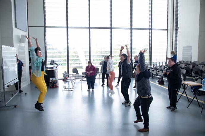 Participants in a studio jumping with their hands up in the air