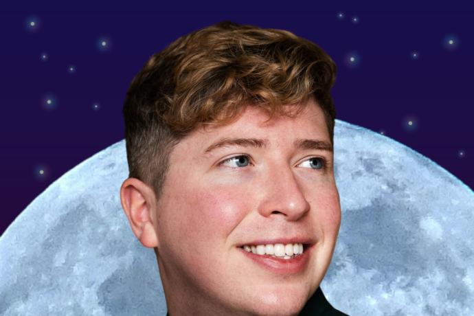 A man poses behind a moon, looking away from the camera and smiling 