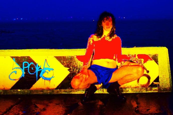 A woman is seated on a bench featuring vibrant graffiti, set against a city backdrop.
