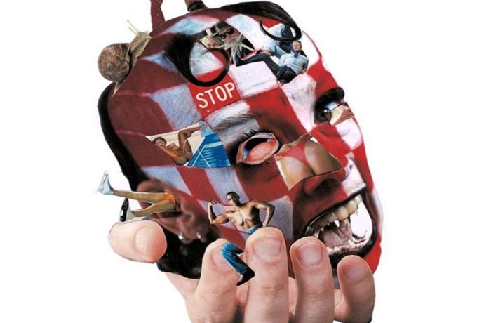 A hand holding a face. There are various characters and designs present on the head.