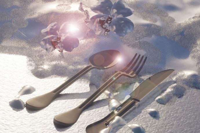 A spoon, fork, and knife rest on a textured white surface with a shadow and glare; two metallic flowers and bright light are in the background.