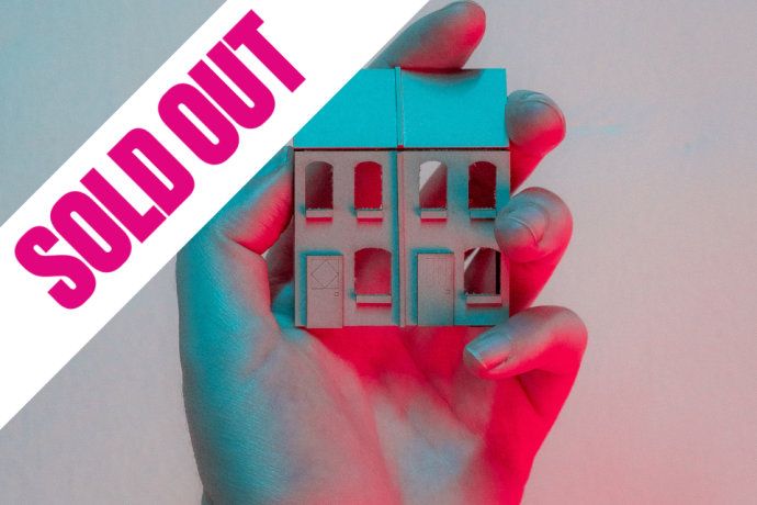  A person gently holds a small house in their hand, symbolizing care and ownership.