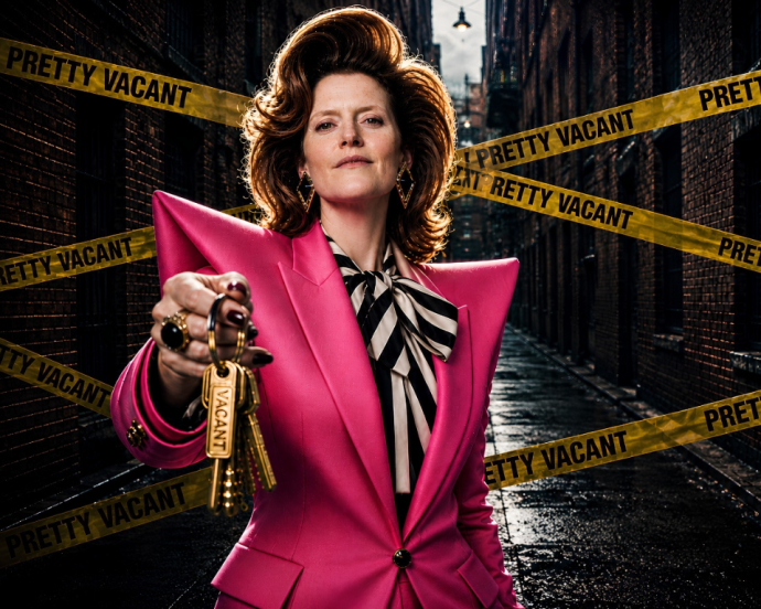 xA person in a bright pink blazer holds a set of gold keys toward the camera in a dark alley lined with yellow "PRETTY VACANT" tape.
