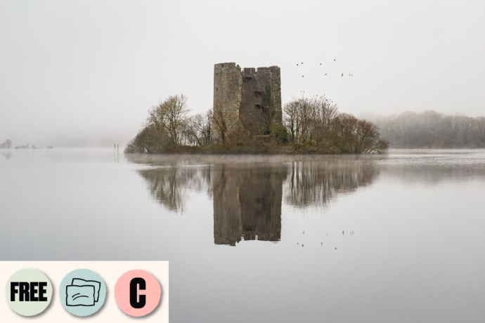 A misty lake surrounds a small island with an old stone tower reflected in the water. Visible access symbols: Creative Captions, Relaxed Performance and Free.