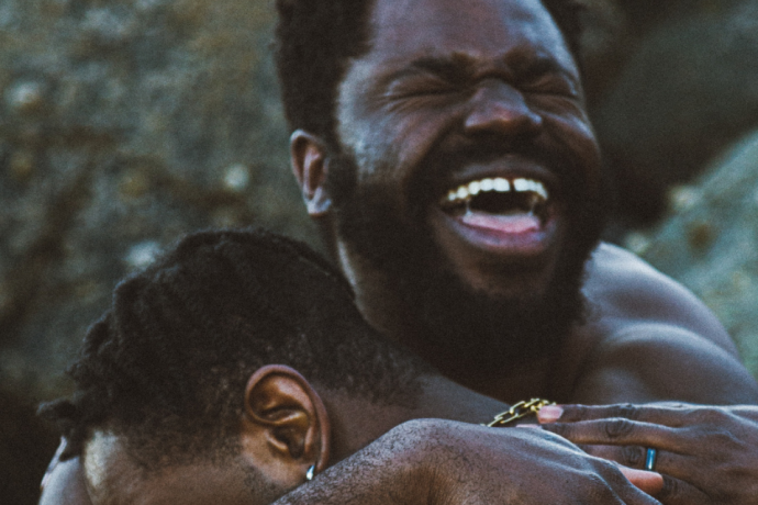Two men embracing in a hug with a wide smile. 