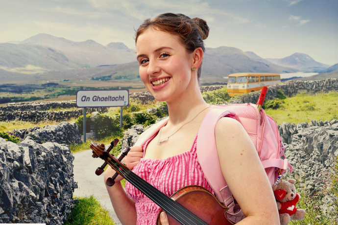 A smiling person wearing a pink backpack holds a fiddle while standing on a rural path lined with stone walls next to an "An Ghaeltacht" road sign. Visible access symbol: ISL