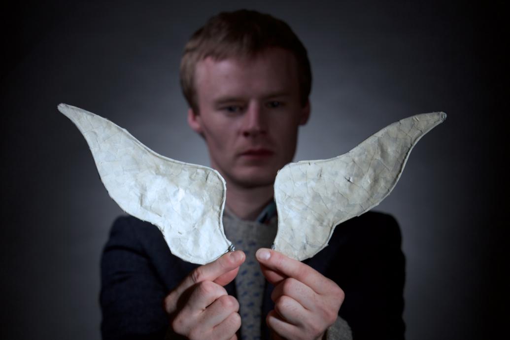 a man holding a small pair of wings in front of him