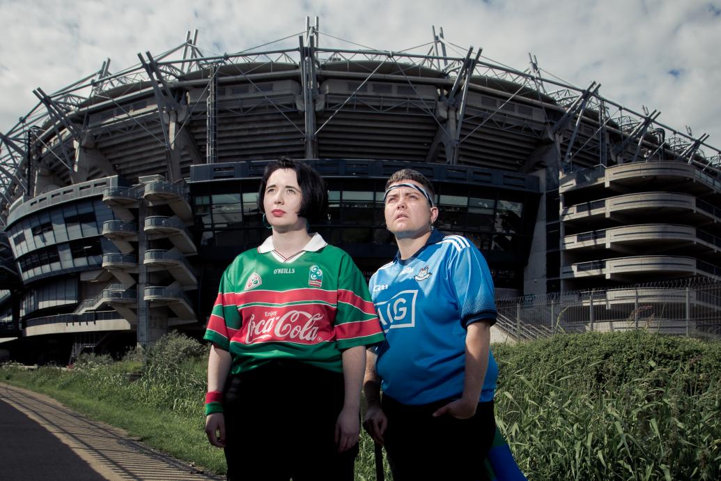 Two people stand in GAA jerseys outside of Croke Park