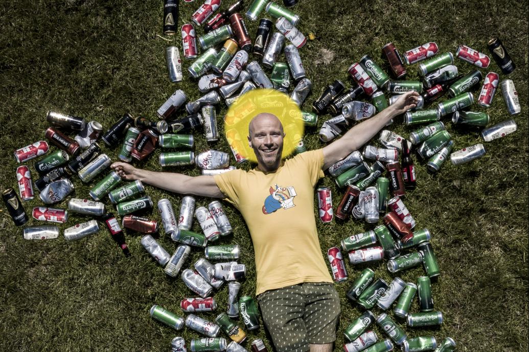 Man lying on a bed of cans in the shape of a crucifix