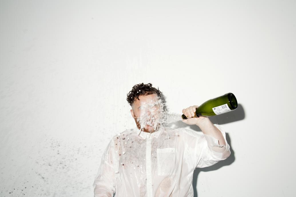 Man throwing prosecco into his face