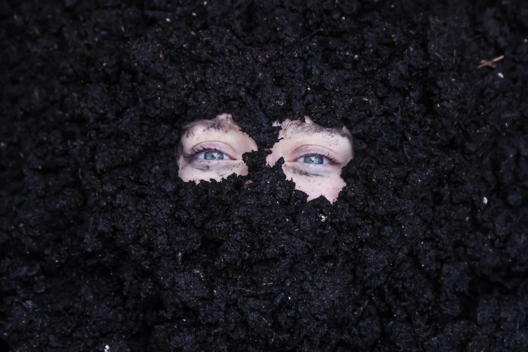 A face buried in the dirt so that only the eyes are visible