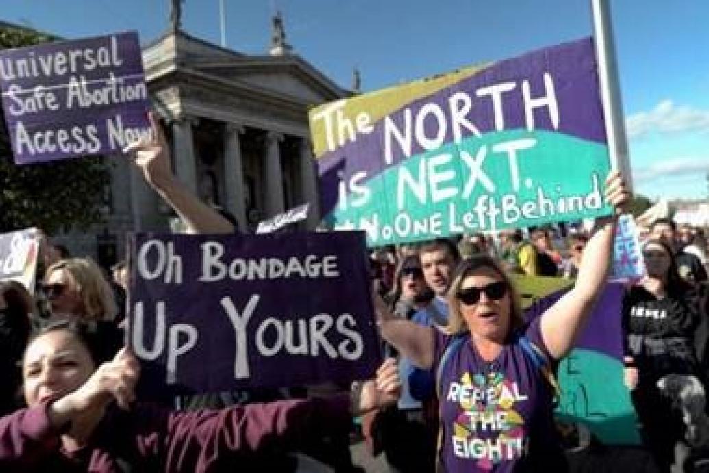 Woman demonstrating outside GPO, holding 'The North is Next' signs