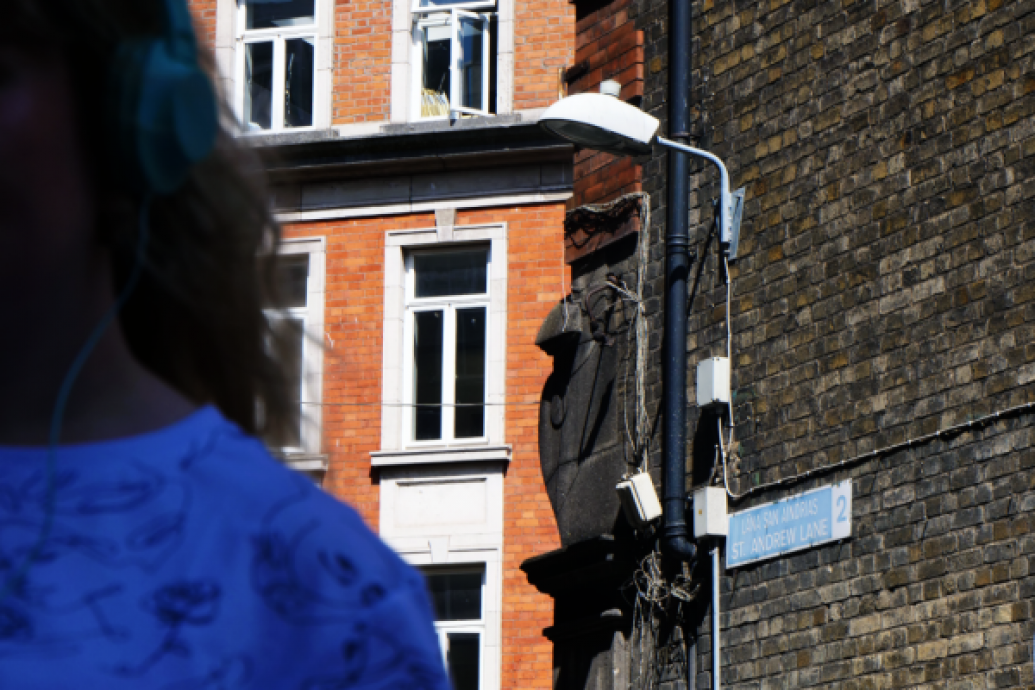 Woman standing in a Dublin lane listening to headphones