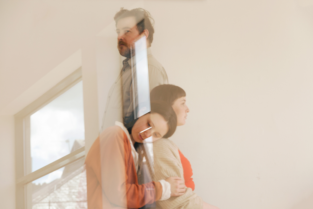 Reflected image of three people in close embrace