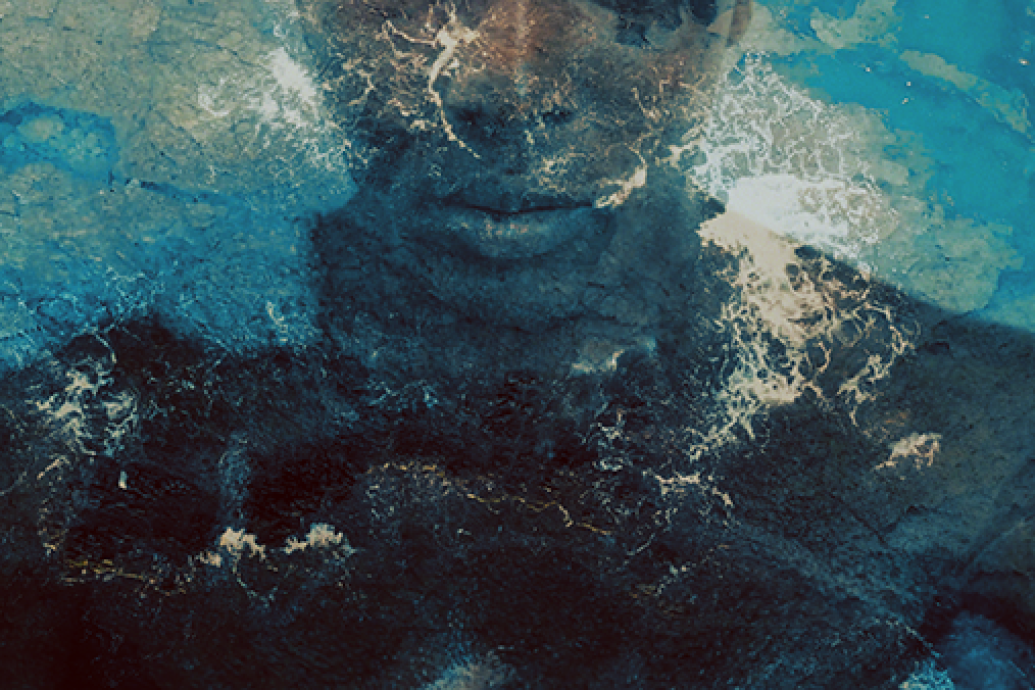 A submerged body underwater with shoulders, neck and lower face in the frame