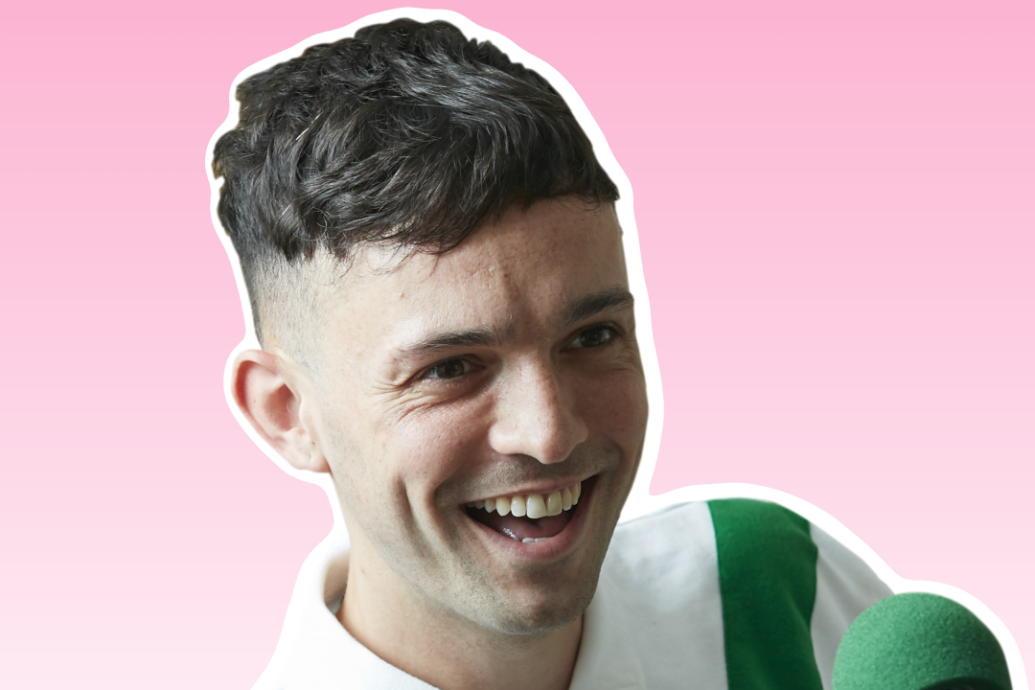 James Kavanagh in front of a microphone against a pink background