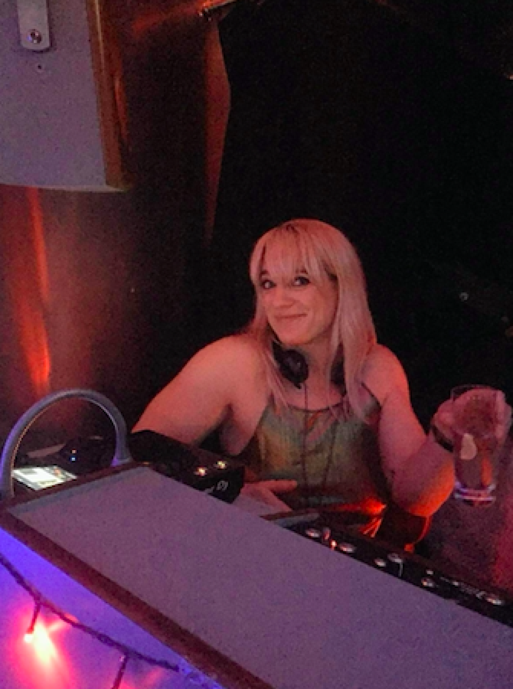 DJ Louise Bruton Djing. Club lighting in red, pink and purple tones.