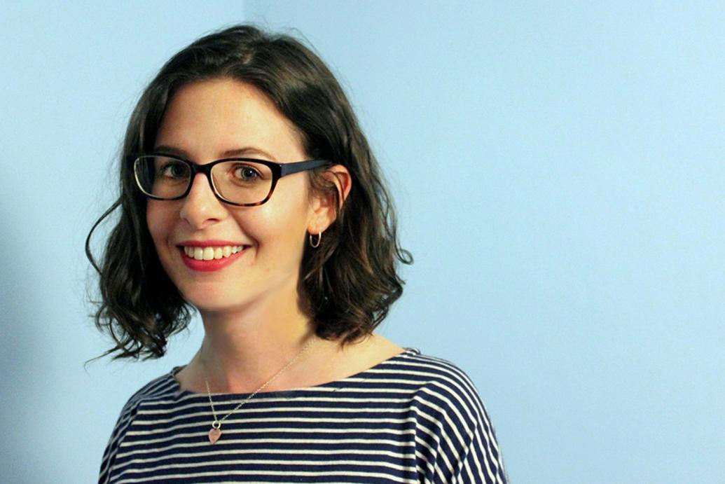 Image of a white woman with a brown bob hair cut and black rimmed glasses smiling to camera