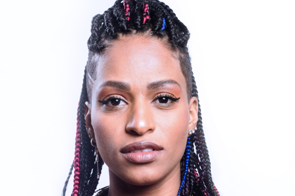 Portrait of a woman with braids looking directly to camera in front of a white background