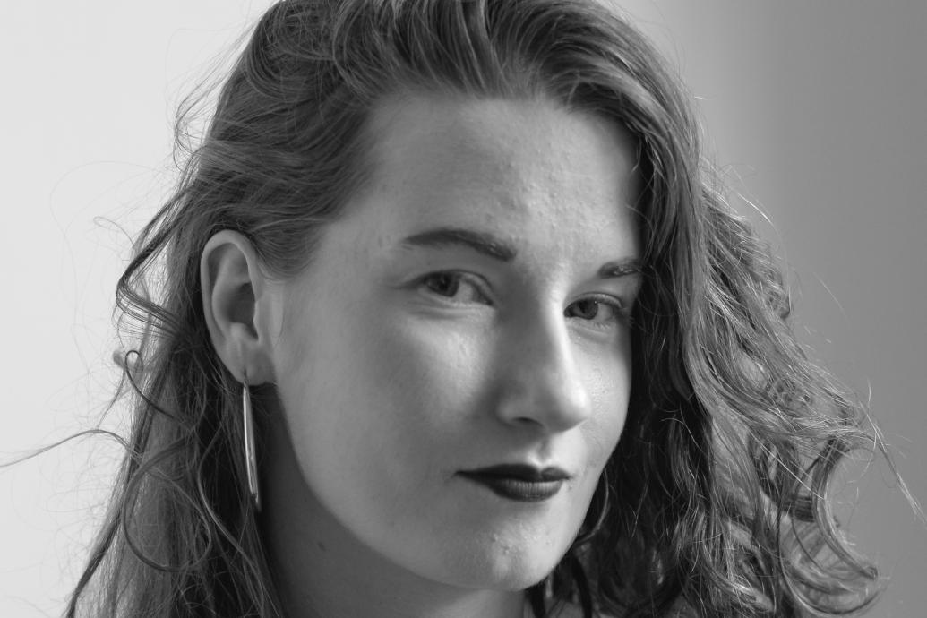 Black and white portrait of a white woman with long curly hair smiling to camera