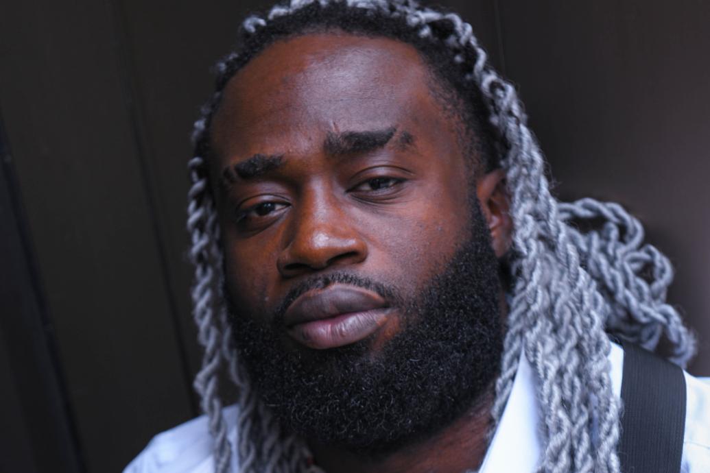 A headshot of a man against a black background.